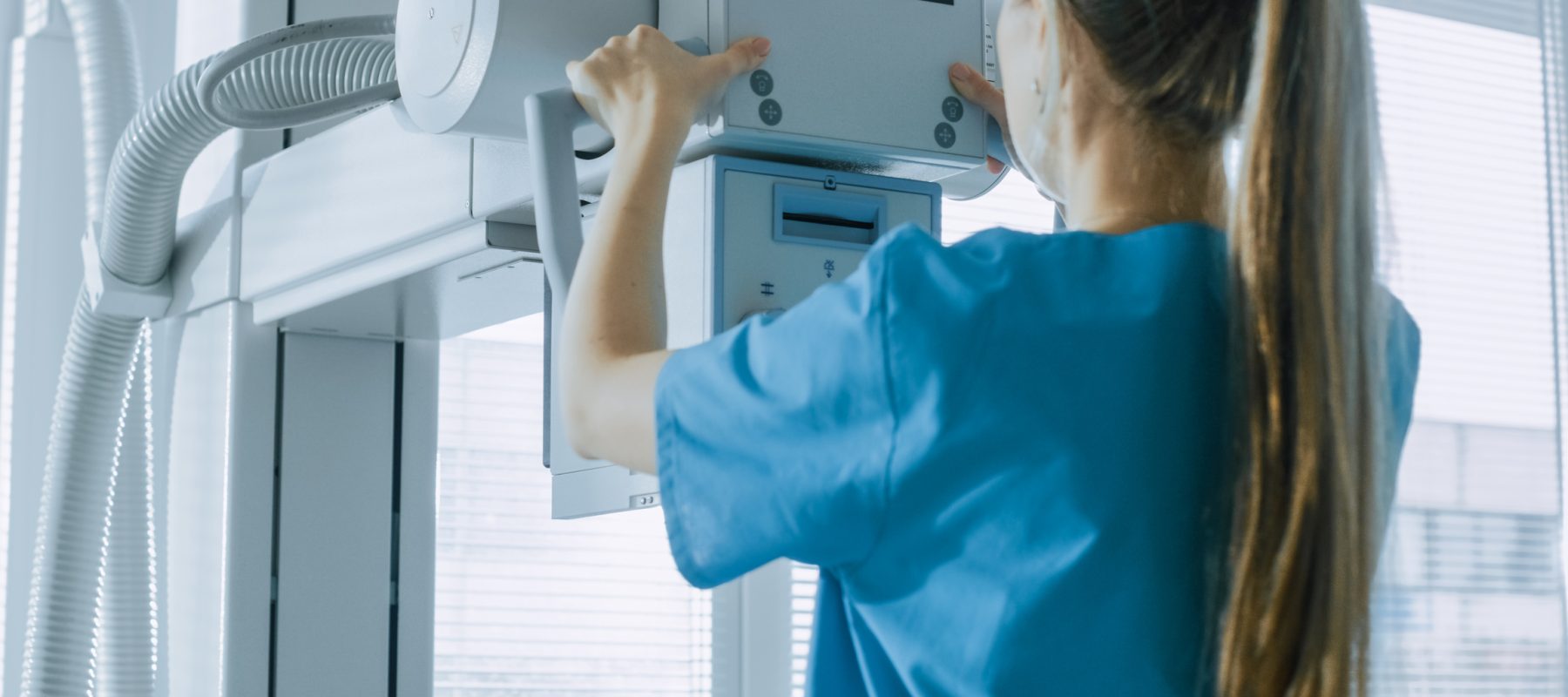 In the Hospital, Female Technician adjusts X-Ray Scanner / Machine. Modern Hospital with Technologically Advanced Medical Equipment and Professional Personnel.